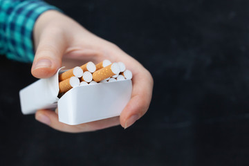 Woman hand with box of cigarettes. Black background