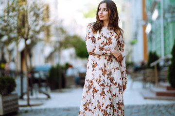 Young woman in a beautiful dress posing on a city street. Beautiful girl enjoy spring time....