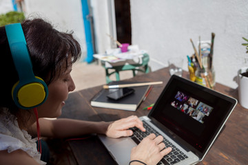 A young woman with headphones making a video call while working at home