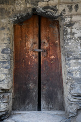 Vintage wooden door closed by a rusty padlock in the village of Dartlo