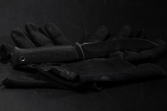 Combat Knife On An Old Black Gloves