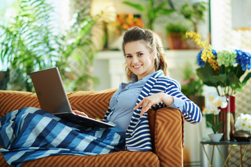 smiling woman with laptop in modern living room in sunny day