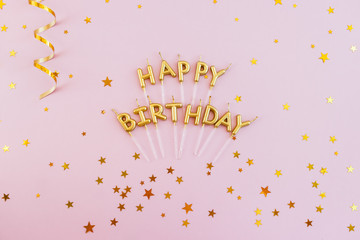 Words happy birthday made by candles on a pink background. Greeting postcard.