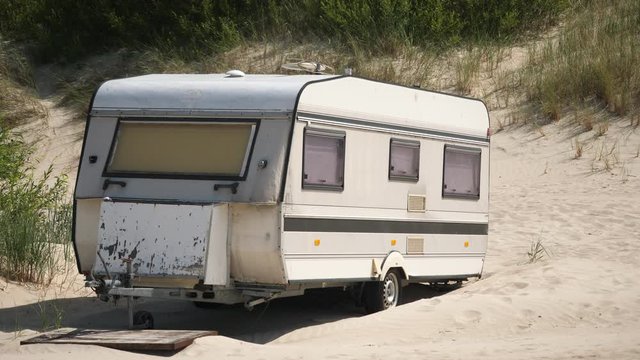 Caravan camper van on Beach. Forbidden old Vintage parked trailer on Sand. Isolated.
