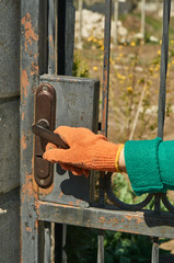 A hand in a working glove opens a metal door