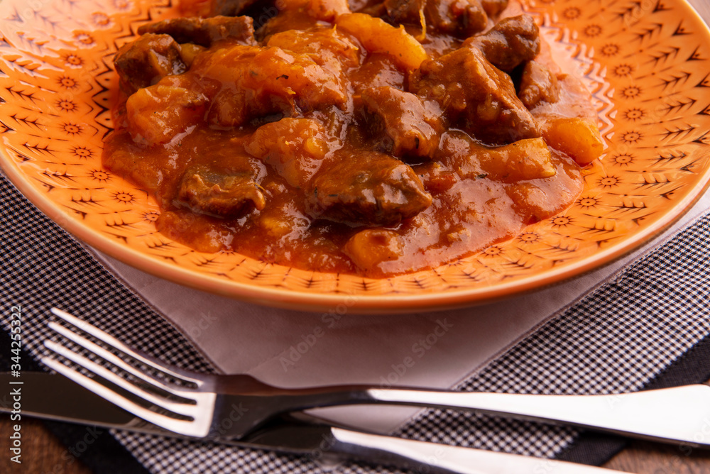 Wall mural bowl with cooked cassava and meat on wooden table