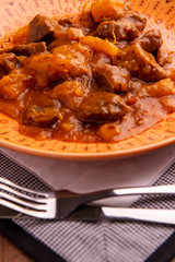 bowl with cooked cassava and meat on wooden table