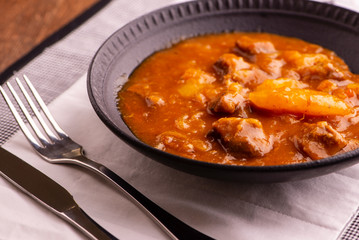 bowl with cooked cassava and meat on wooden table