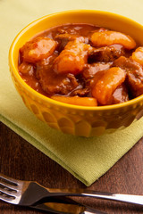 bowl with cooked cassava and meat on wooden table