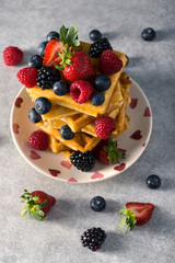 Traditional homemade Belgian waffles with fresh summer berries, blueberry raspberry, strawberry and blackberry. Delicious breakfast.