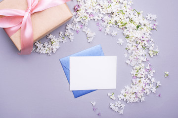 Envelope with an empty letter with a gift, lilac flowers. Holiday content.