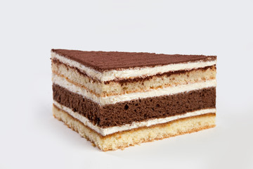 Slice of Tiramisu cake isolated on white background. Layered pastry desert with cream.