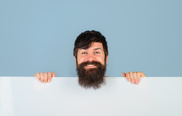 Copy space. Advertising. Bearded man with blank board. Space for text. Smiling man holds empty board. Advertising banner. Handsome man shows empty board. Ready for your text or product.