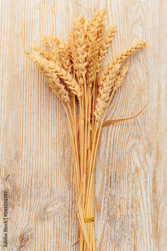 Wall mural bunch of wheat ears on wooden table. sheaf of wheat on vintage background.