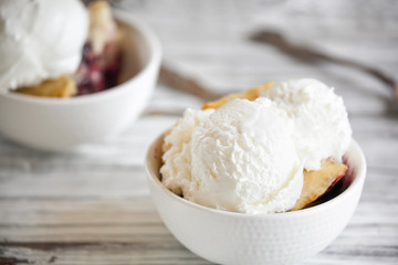 Fresh made homemade cherry cobbler served with two scoops of vanilla ice cream. Selective focus with blurred background.