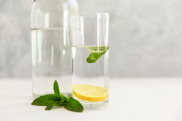Glass water bottle on a light background, a glass of water with lemon, the concept of a healthy lifestyle and a healthy diet, eco storage,