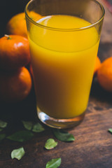 Amazing orange juice's glass on the rustic wood table. We could see fresh oranges fruit on the background.