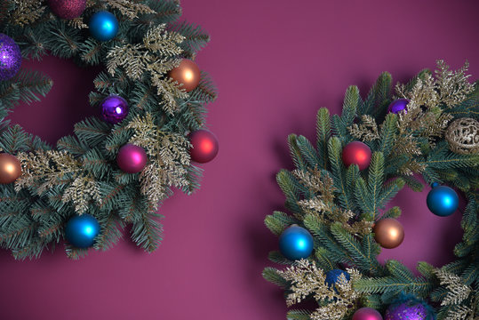 New Year decoration. Christmas background. Coniferous wreaths with balls on a purple background.