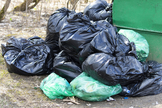 Black and green garbage bags filled with garbage. Save the planet concept.