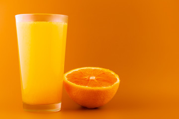 Glass of orange juice isolated on orange background