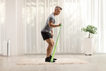 Fit young man exercising with an elastic band at home