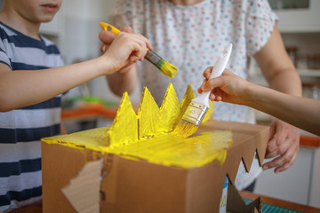 Brothers painting a cardboard dinosaur costume