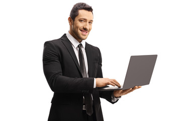 Young man in a suit holding a laptop computer and looking at the camera