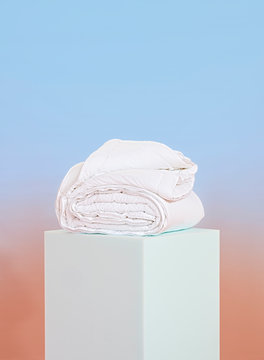 Folded Comforter On Pastel Pedestal