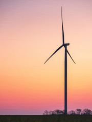Fototapeta premium silhouette of wind generator in sunset sky with copy space in vertical view