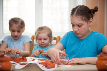 Three girls  sculpting dishes out of clay
