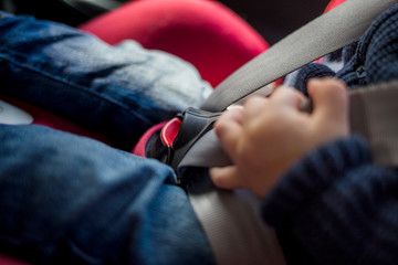 Seat belts close-up. a little boy in a red car seat. Safety of transportation of children in the car.