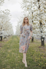 Girl in a flowering garden. Spring garden. Cheerful girl between trees with flowers. Cherry blossom