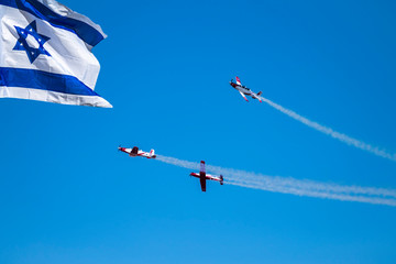 Streaming Israeli Flag and Air Acrobatic flight reciprocating aircraft Israeli group showing flying skills on the Parade of Independence Day of Israel
