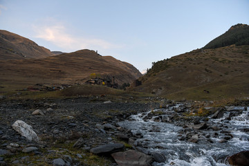 The medieval  village of Dartlo with mountains in the background and a river in the foreground.