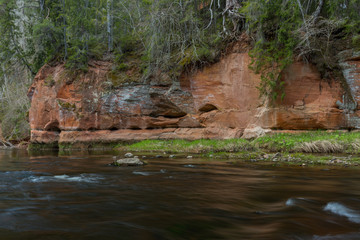 City Cesis, Latvia. River in spring with sandstone cliffs and caves.