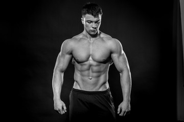 Fototapeta premium Sexy młody sportowiec pozowanie na czarnym tle w Studio. Fitness, kulturystyka, czarno-białe
