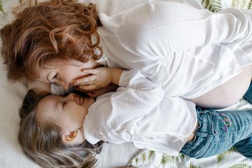 Mother daughter moments. pregnant woman lying on the bed with her little girl