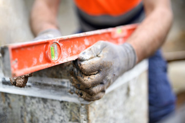 Construction worker checking the bubble level while working at construction site. Building...