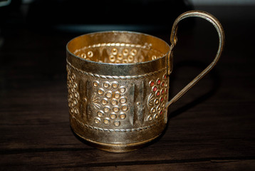 The image of yellow copper vintage cup holder. Old soviet cup holder for faceted glass.