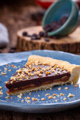 A piece of chocolate brownie with nuts in a blue plate on a wooden background