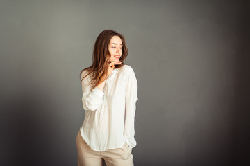 Young girl in a white shirt on a gray background. French woman in white blouse against a background of gray walls. Without retouching. Without make-up.