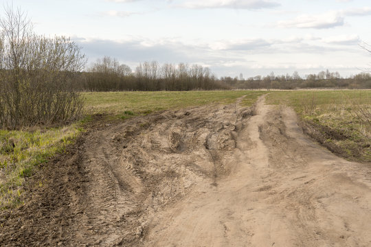 dirt damaged rural spring road in a field. concept of problem with the roads