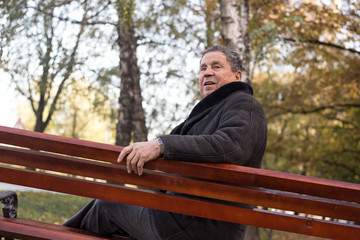 Fototapeta premium Portrait of happy senior man smiling, in the public park, outdoors. Old man relaxing outdoors and looking away. Portrait of elderly man enjoying retirement