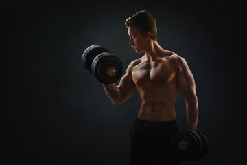 Naklejka na ściany i meble Muscular man with dumbbells on black background