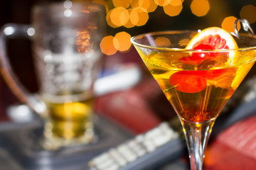 Martini glass holding yellow liquid, cherries and an orange.
