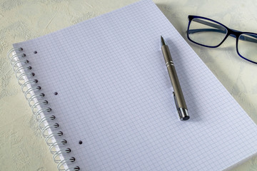 Large notebook, pen and glasses on a light background