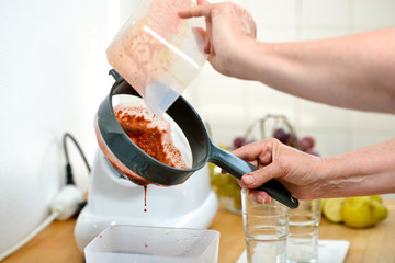 woman filtering fruit and vegetable juice with a sieve