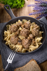 Pork meatballs with noodles in a cast iron skillet.