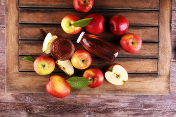 Apple cider drink and organic apples with leaves on table
