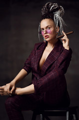 Young beautiful woman with dreadlocks hairstyle in sexy checkered suit dressed on a naked body...
